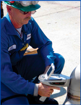 Figure 1. An inspector using a handheld XRF analyzer on piping.